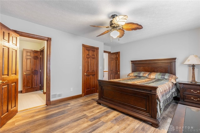 bedroom with ceiling fan, ensuite bathroom, hardwood / wood-style floors, and a textured ceiling