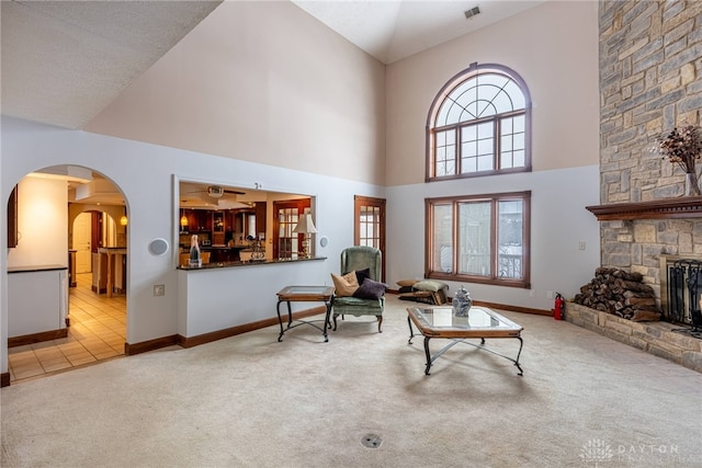 living room with light colored carpet, a fireplace, and a high ceiling