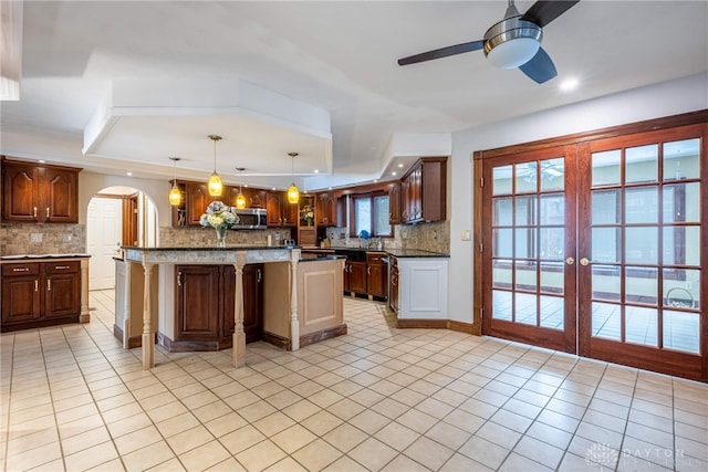 kitchen featuring light tile patterned flooring, a center island, decorative light fixtures, and decorative backsplash