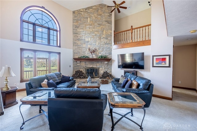 carpeted living room featuring ceiling fan, a stone fireplace, and high vaulted ceiling