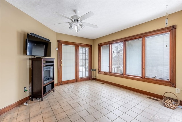 unfurnished living room with ceiling fan, light tile patterned floors, and a textured ceiling