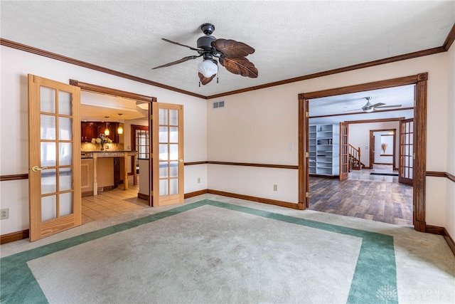 unfurnished room featuring light carpet, crown molding, french doors, and a textured ceiling