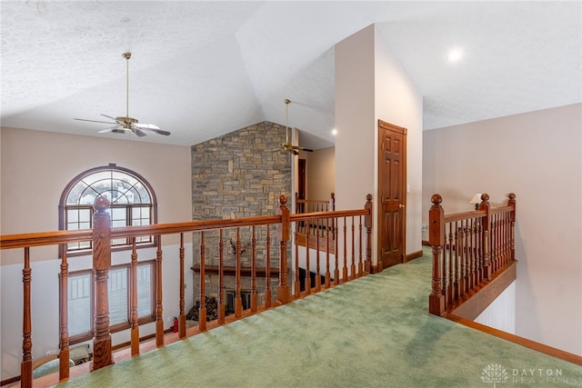 hallway with vaulted ceiling, a textured ceiling, and carpet flooring