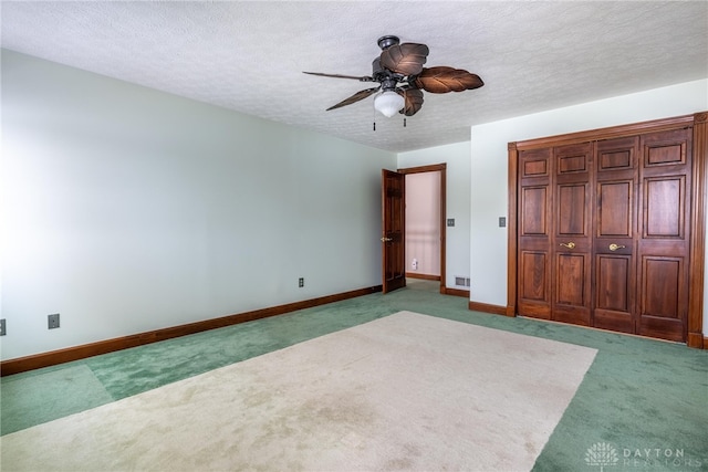 unfurnished bedroom with a textured ceiling, carpet floors, and ceiling fan