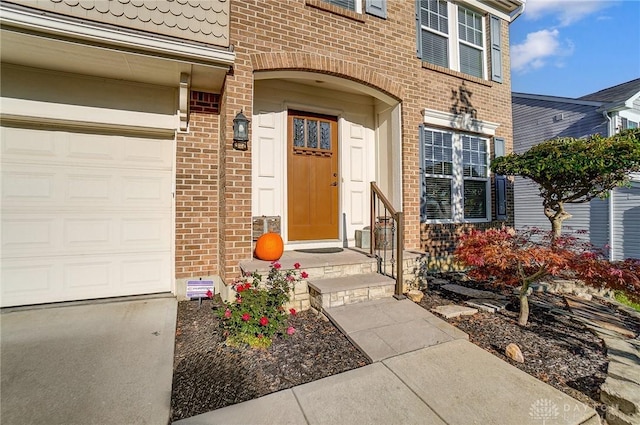 entrance to property featuring a garage and brick siding