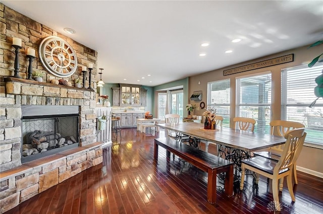 dining area featuring a stone fireplace, recessed lighting, baseboards, and dark wood-style flooring