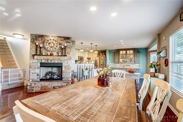 dining space with a stone fireplace and dark hardwood / wood-style flooring