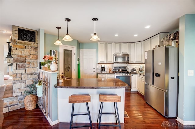 kitchen featuring backsplash, dark hardwood / wood-style flooring, a breakfast bar, pendant lighting, and stainless steel appliances