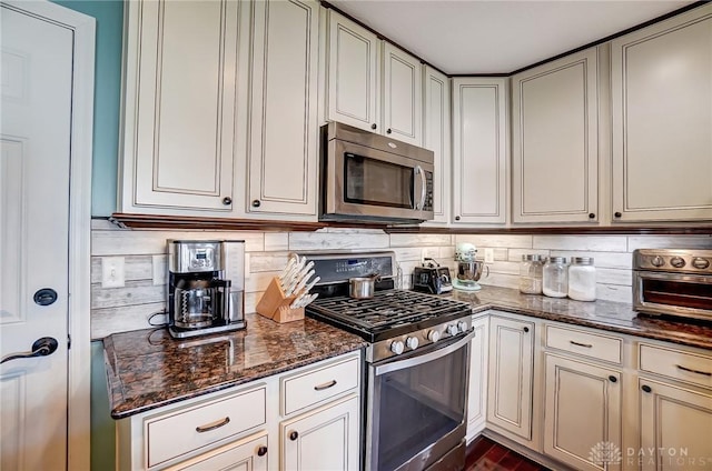 kitchen featuring dark stone counters, backsplash, appliances with stainless steel finishes, and a toaster