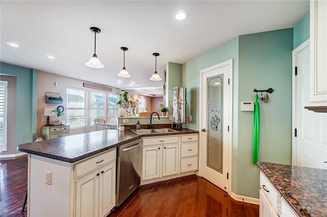 kitchen with a sink, dishwasher, a peninsula, hanging light fixtures, and dark wood-style flooring