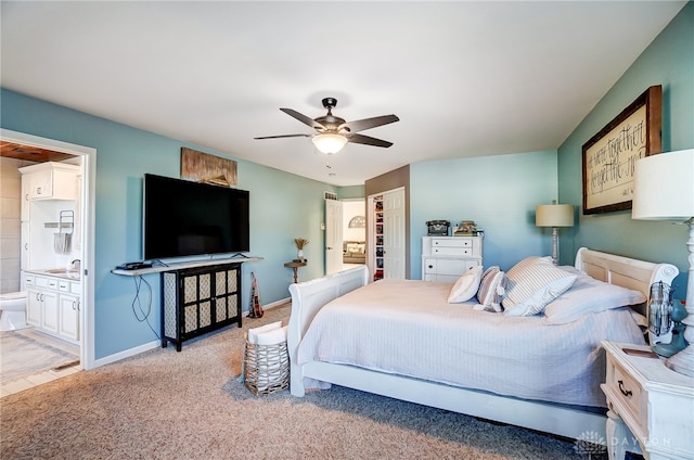 carpeted bedroom with ensuite bath, sink, and ceiling fan