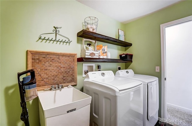 clothes washing area featuring washing machine and clothes dryer, baseboards, carpet floors, laundry area, and a sink