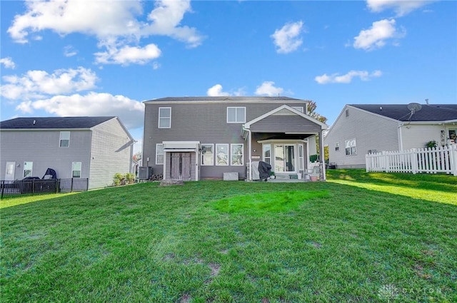 rear view of property featuring central air condition unit, a lawn, and fence