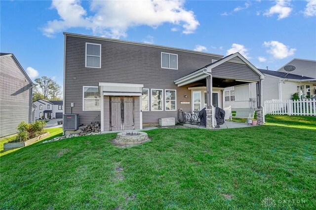 rear view of house featuring a patio, central AC, a fire pit, and a lawn