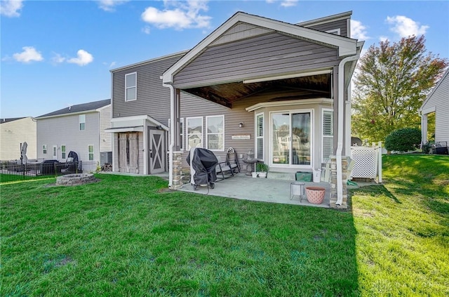 back of house featuring a patio, fence, a lawn, and an outbuilding