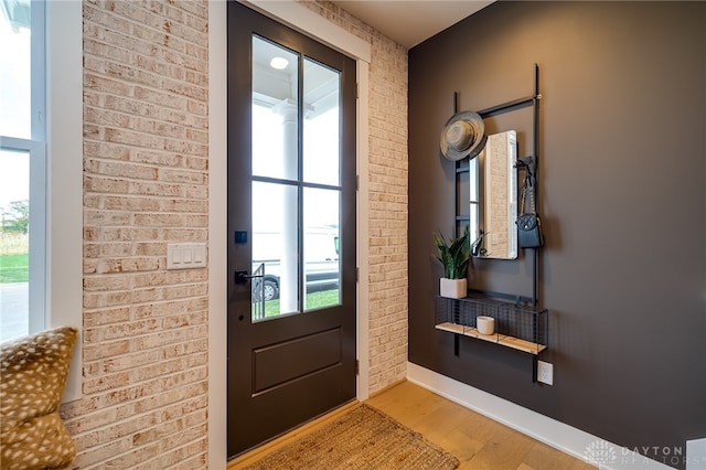 doorway with brick wall and light wood-type flooring