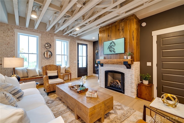 living room featuring beamed ceiling, light wood-type flooring, and a fireplace