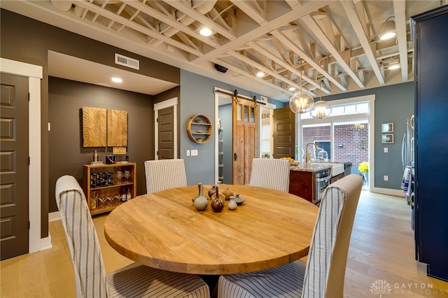 dining space featuring light wood-type flooring and a barn door