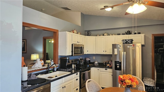 kitchen with lofted ceiling, white cabinets, ceiling fan, appliances with stainless steel finishes, and sink