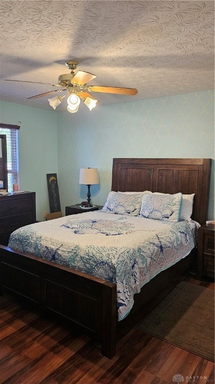 bedroom with a textured ceiling, dark wood-type flooring, and ceiling fan