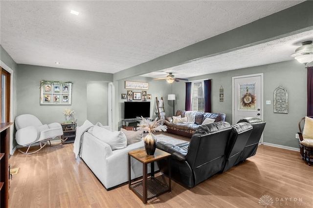 living area with ceiling fan, baseboards, light wood finished floors, and a textured ceiling