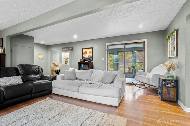 living room with recessed lighting, light wood-type flooring, and a textured ceiling