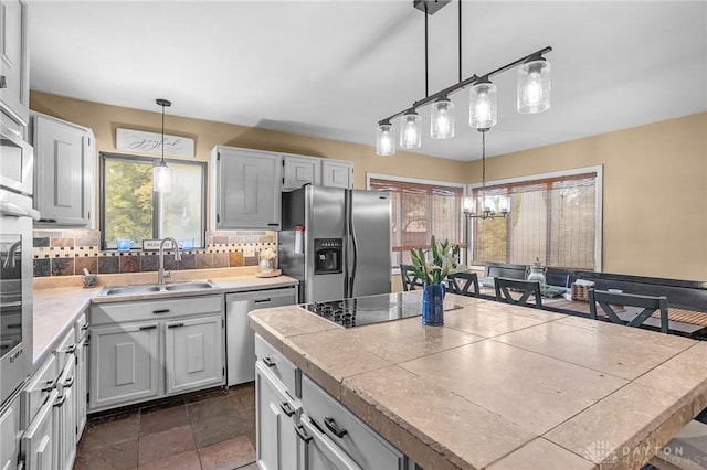 kitchen with tasteful backsplash, a center island, hanging light fixtures, stainless steel appliances, and a sink