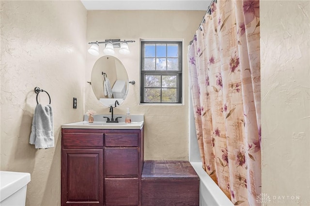 bathroom with vanity, shower / tub combo, and a textured wall