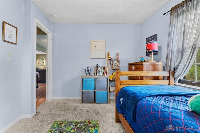 bedroom with carpet, baseboards, and a textured ceiling