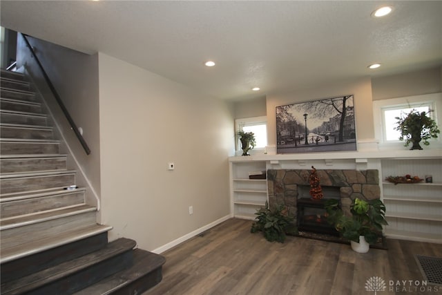 living room with a stone fireplace and dark hardwood / wood-style floors