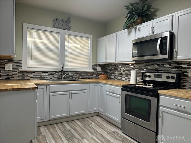 kitchen with white cabinets, wooden counters, stainless steel appliances, and sink