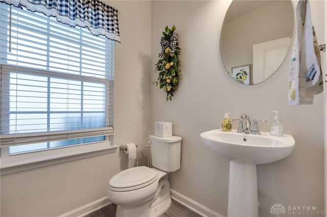 half bath featuring toilet, baseboards, and a sink