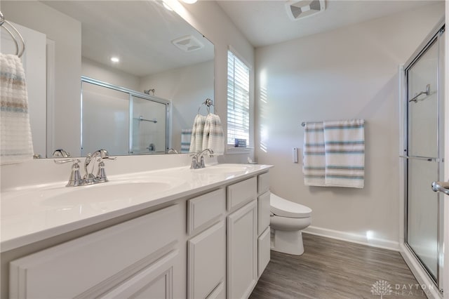 bathroom with a sink, wood finished floors, toilet, and a stall shower