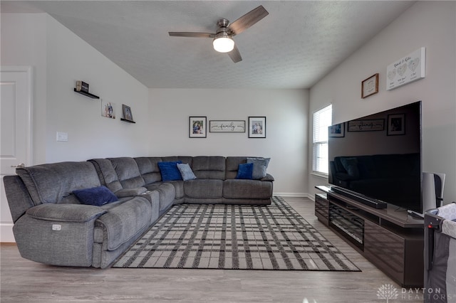 living area with a textured ceiling, a ceiling fan, and wood finished floors