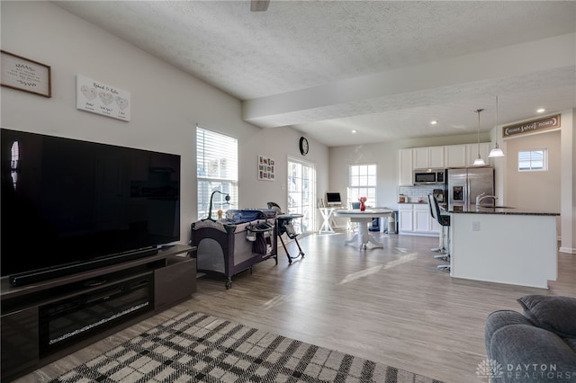 living room featuring recessed lighting, light wood-style floors, and a textured ceiling