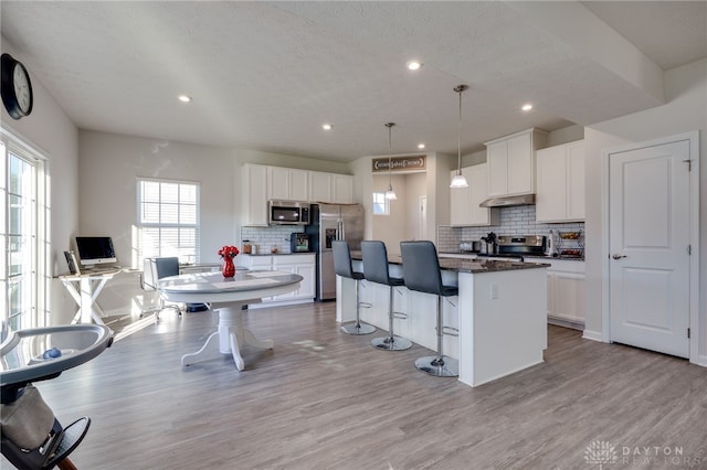 kitchen featuring a kitchen island, light wood-style flooring, a kitchen breakfast bar, and stainless steel appliances