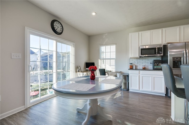 kitchen with dark countertops, dark wood finished floors, decorative backsplash, stainless steel appliances, and white cabinetry