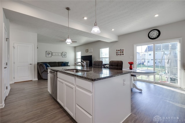 kitchen featuring a sink, dark stone countertops, dark wood-style floors, open floor plan, and white cabinetry