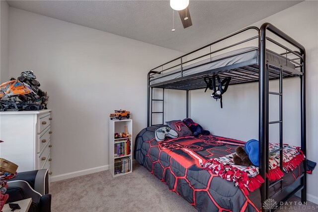 bedroom with ceiling fan, light colored carpet, and a textured ceiling