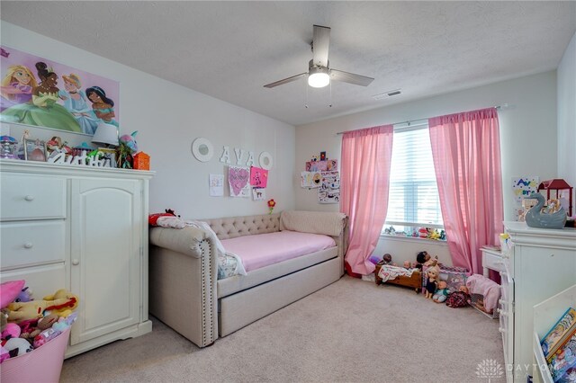 bedroom featuring a textured ceiling, ceiling fan, and light carpet