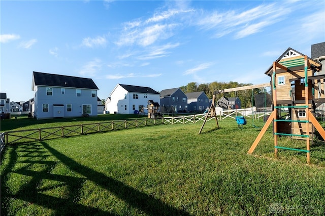 view of playground with a yard, fence, and a residential view