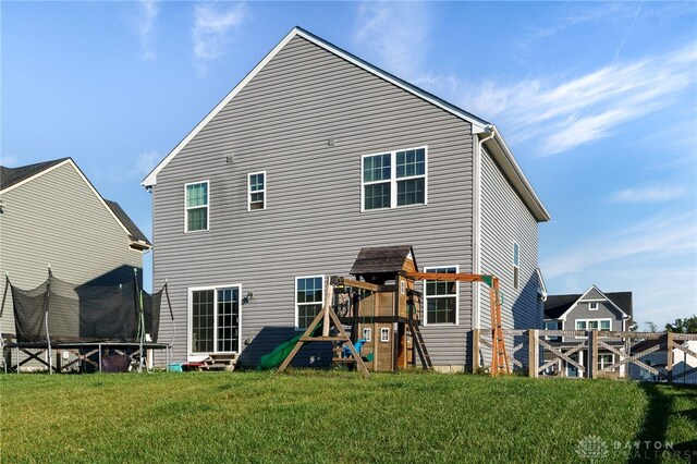 back of property with a playground, a yard, and a trampoline