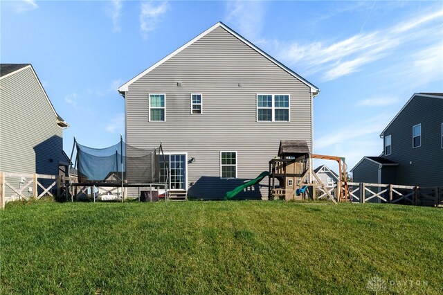 back of property featuring a trampoline and a lawn