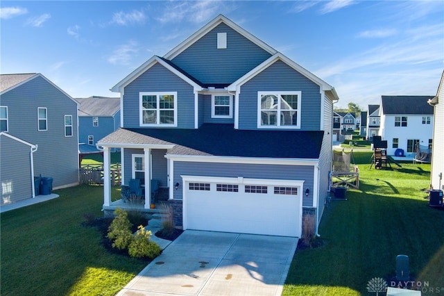 craftsman inspired home featuring concrete driveway, an attached garage, fence, and a front lawn