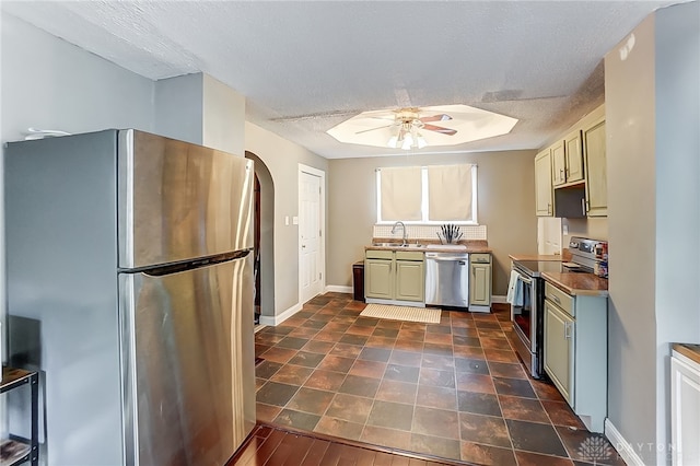 kitchen with a textured ceiling, ceiling fan, sink, and appliances with stainless steel finishes