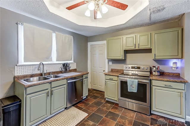 kitchen featuring appliances with stainless steel finishes, a textured ceiling, a tray ceiling, and sink