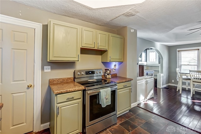 kitchen with stainless steel range with electric cooktop, cream cabinets, ceiling fan, a textured ceiling, and dark hardwood / wood-style flooring