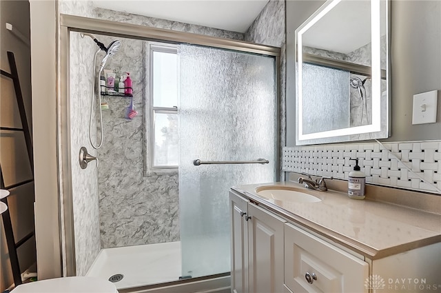 bathroom with vanity, a shower with shower door, and backsplash