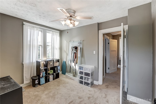 misc room featuring ceiling fan, light colored carpet, and a textured ceiling