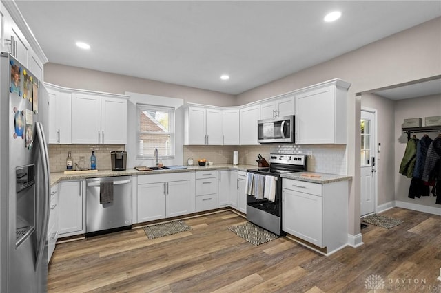 kitchen featuring dark wood-type flooring, white cabinets, sink, light stone countertops, and stainless steel appliances